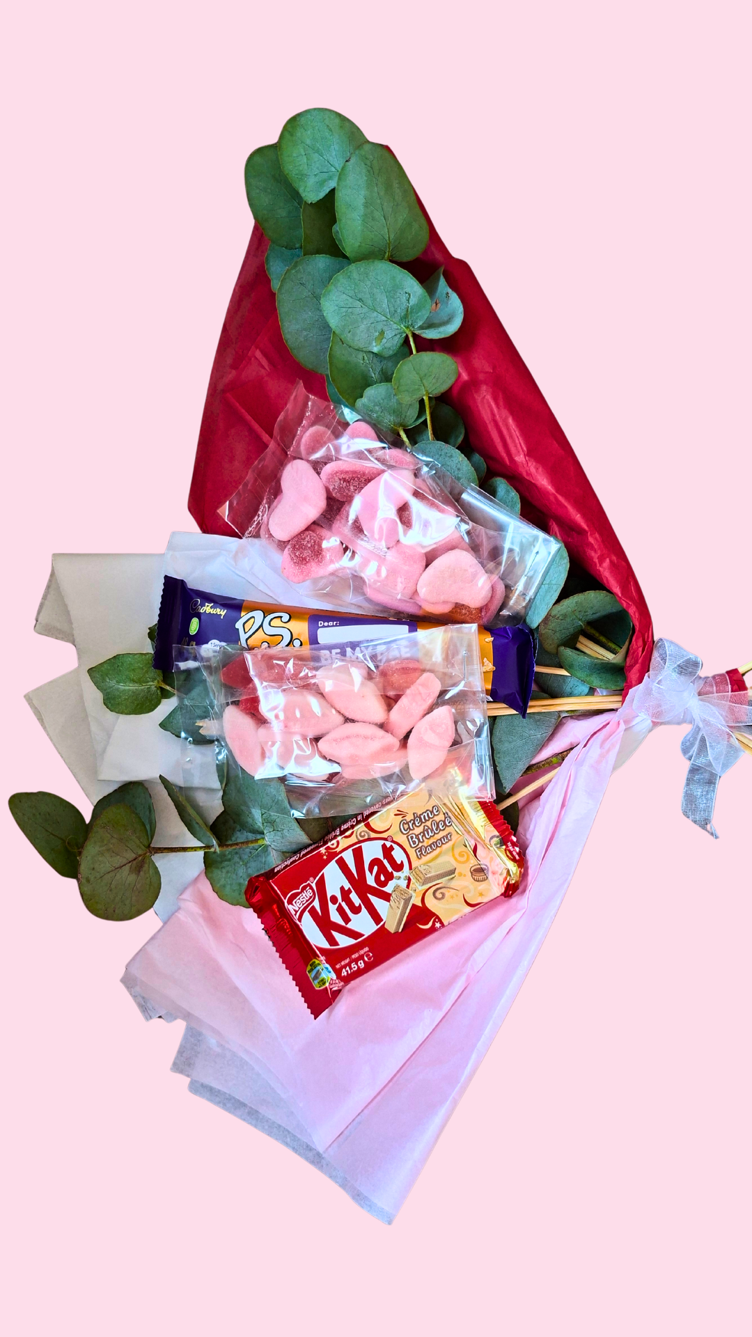 Bouquet of pink candies and Kit Kats with green leaves on a pink background